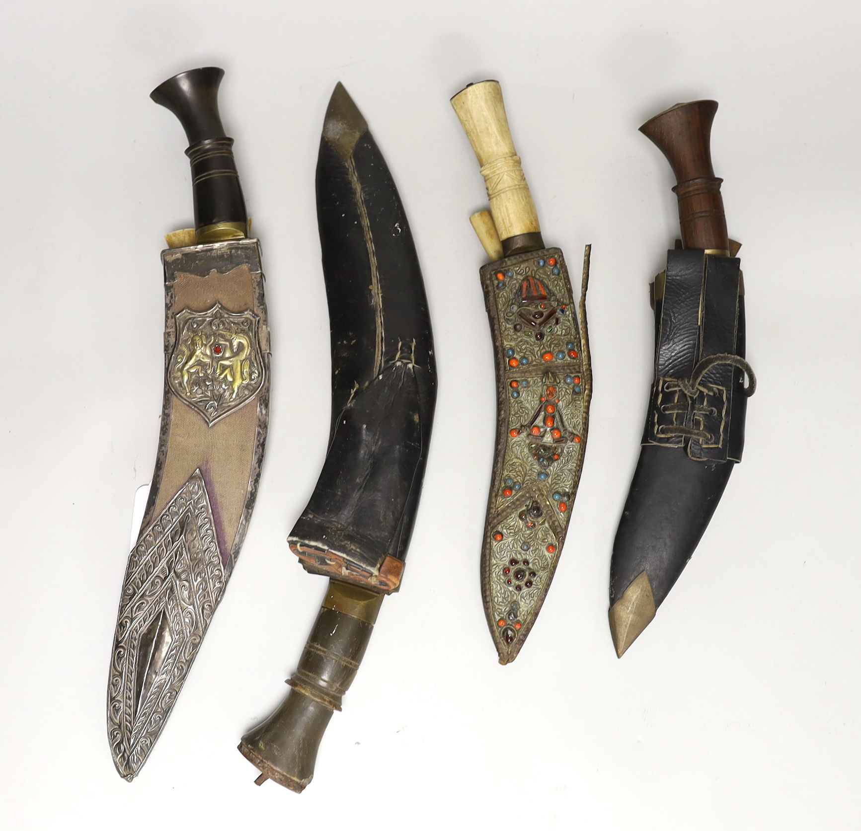 A kukri within white metal mounted sheath, blade 27cm, and three others, one with bone handle
